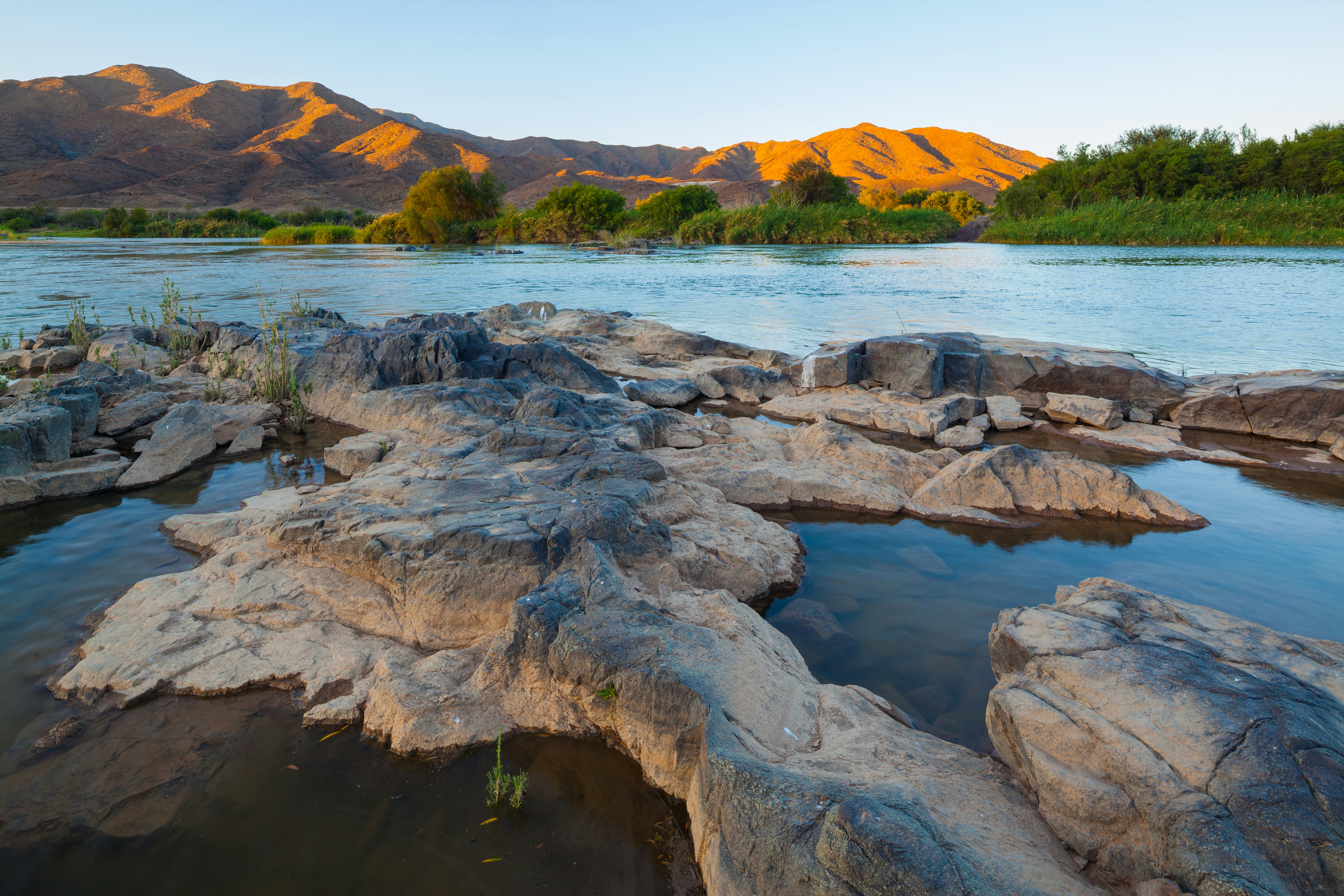 brown and gray rock formation on body of water during daytime, Sunset over the Orange river at the South-Africa Namibia border