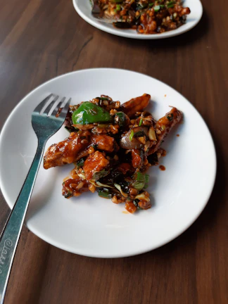 Close-up of a beautifully plated spicy Szechuan stir-fry with fresh chilies and vibrant vegetables.