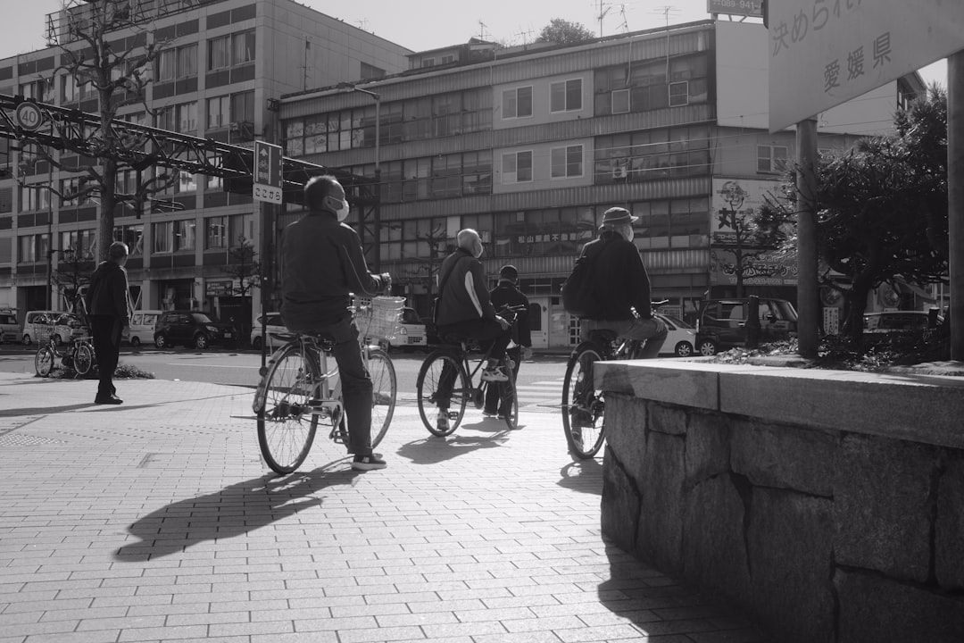 grayscale photo of 2 men riding bicycle on sidewalk