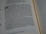 A close-up view of a Bible passage, focusing on a section of text with chapter and verse numbers visible. The text is formatted in two columns on a cream-colored page with thin black lines separating sections.
