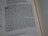 A close-up view of a Bible passage, focusing on a section of text with chapter and verse numbers visible. The text is formatted in two columns on a cream-colored page with thin black lines separating sections.