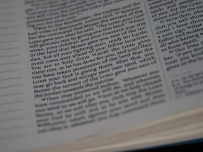 Close-up view of an open book with text. The text appears to be religious or biblical, as it references 'the LORD' multiple times.