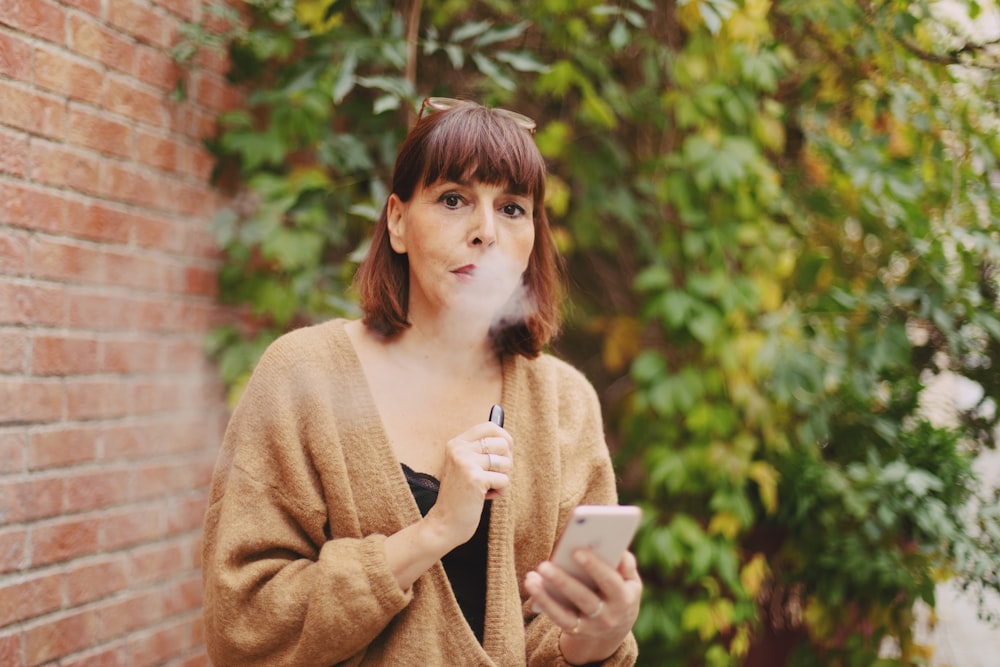 woman in brown sweater holding white ceramic mug