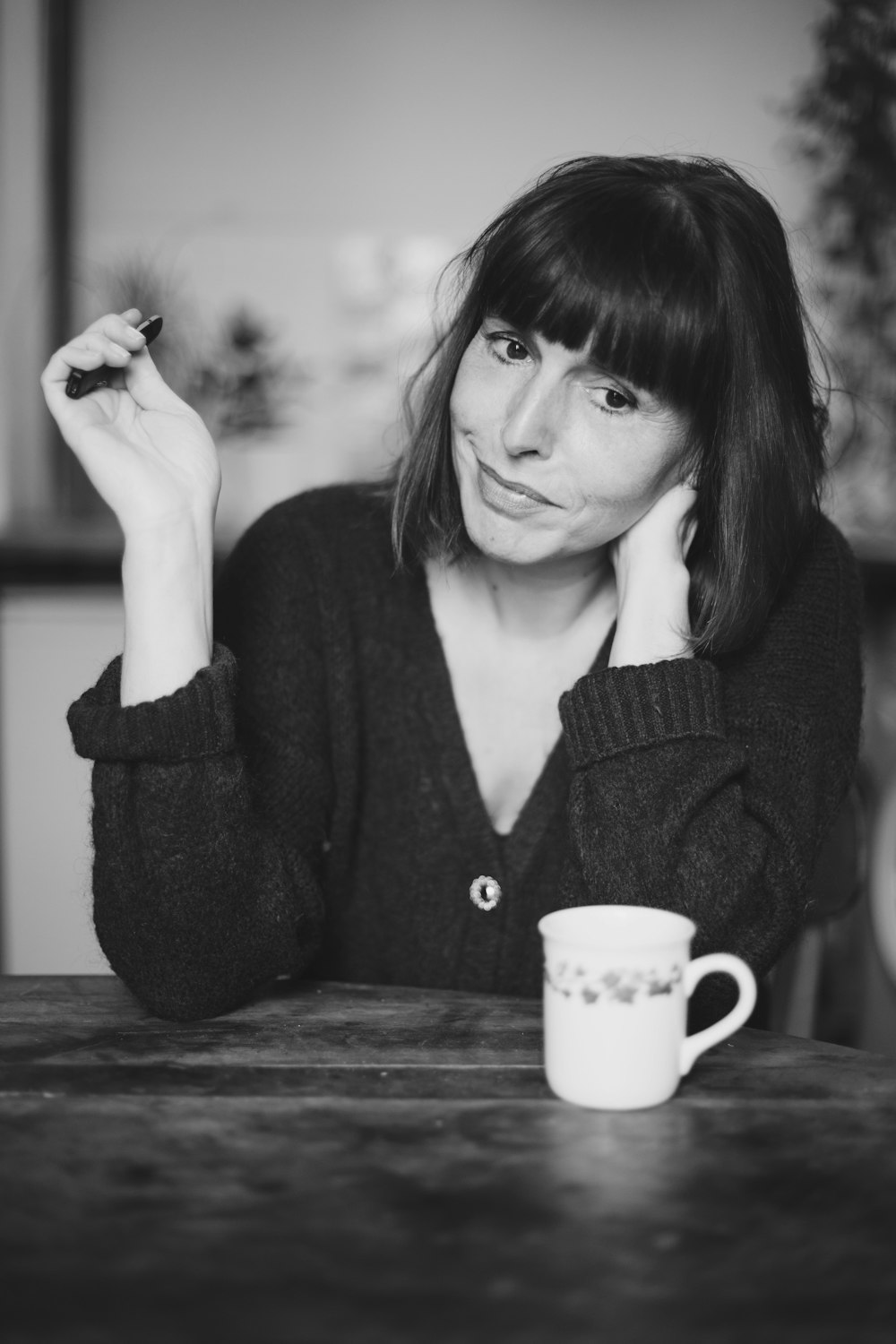 woman in black knit sweater holding white ceramic mug