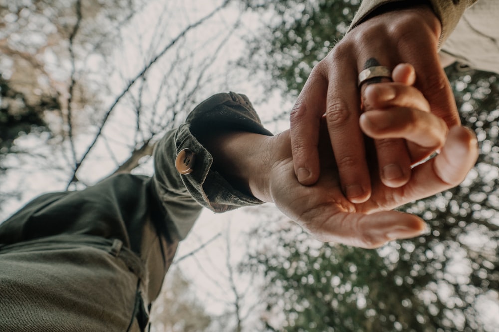 person in black leather jacket holding persons hand