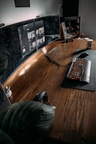 A cozy workspace desk with gaming monitors and artwork scattered around.