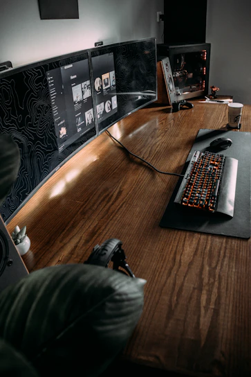 A calm, modern workspace showing a focused companion monitoring a Roblox gameplay session on a laptop.