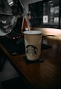 white and black disposable cup on brown wooden table