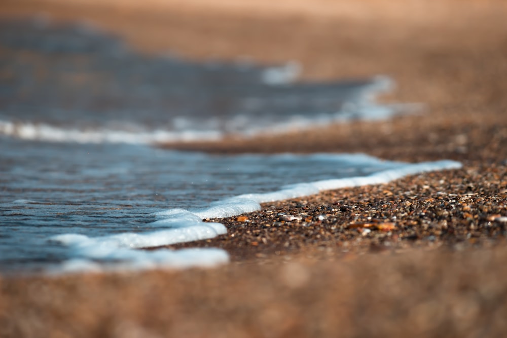 日中の茶色の砂浜に波打つ水
