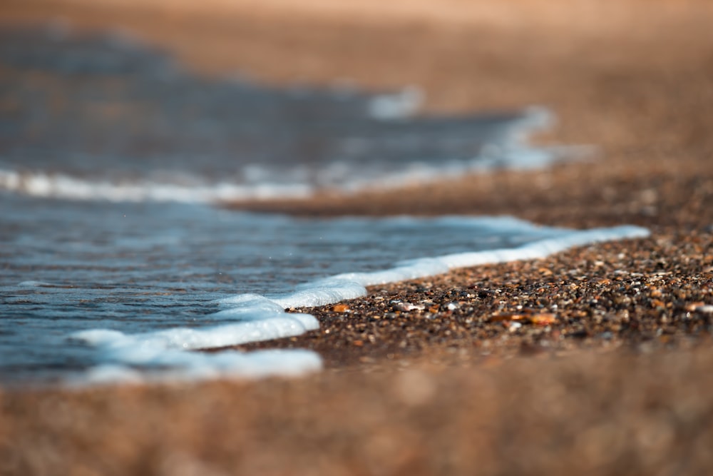 onde d'acqua sulla sabbia marrone durante il giorno