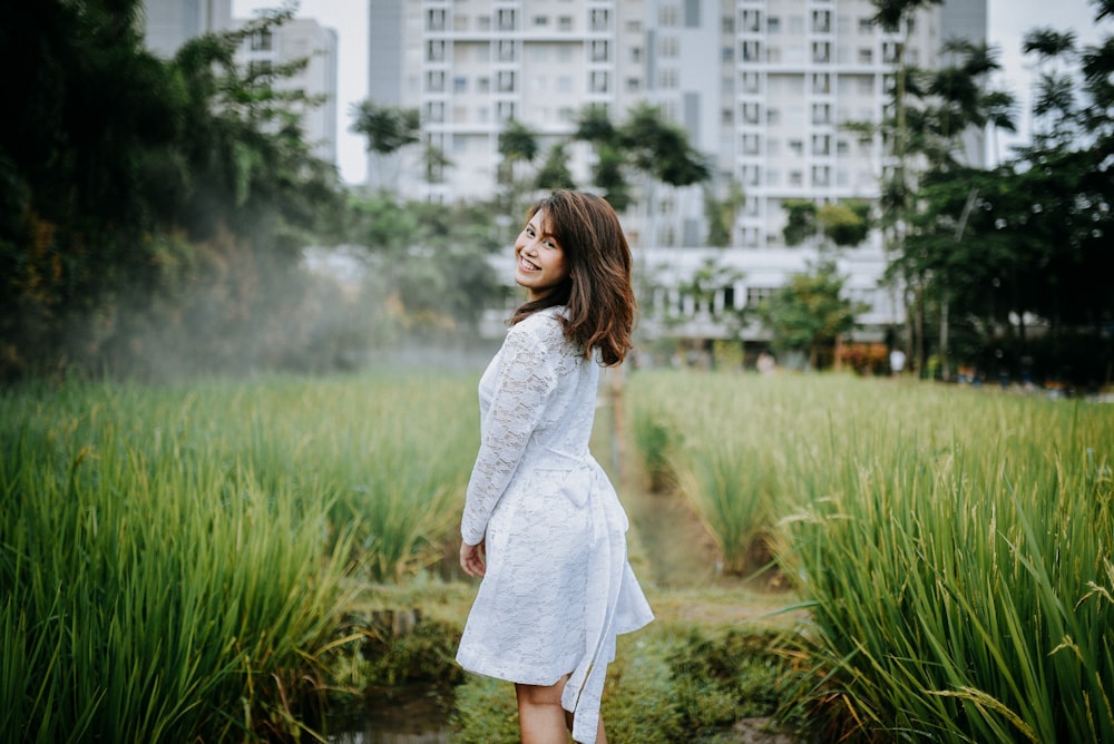 donna in abito bianco a maniche lunghe in piedi sul campo di erba verde durante il giorno