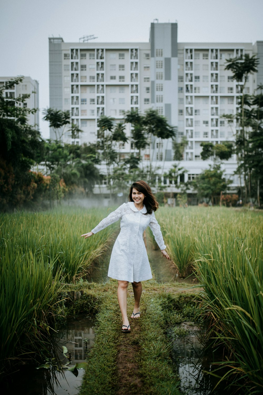 woman in white long sleeve dress standing on green grass field during daytime