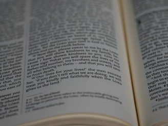 A close-up view of a book, revealing text printed in two columns. The focus is on a specific paragraph with words like 'lives for your lives', suggesting a dramatic or significant context, possibly from a religious or historical text.