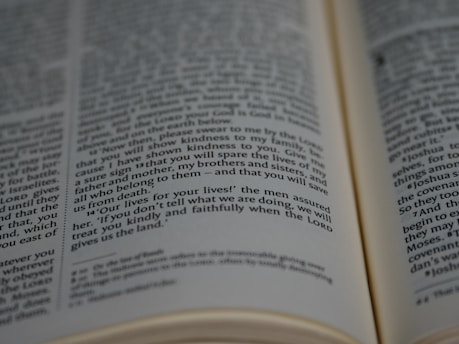 A close-up view of a book, revealing text printed in two columns. The focus is on a specific paragraph with words like 'lives for your lives', suggesting a dramatic or significant context, possibly from a religious or historical text.