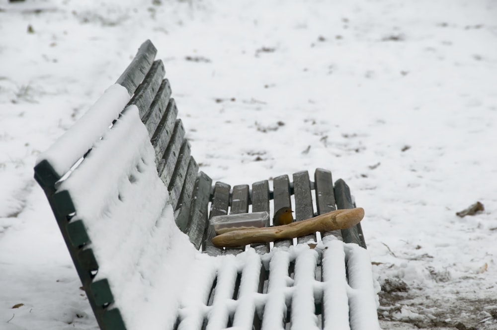 brown wooden bench covered with snow