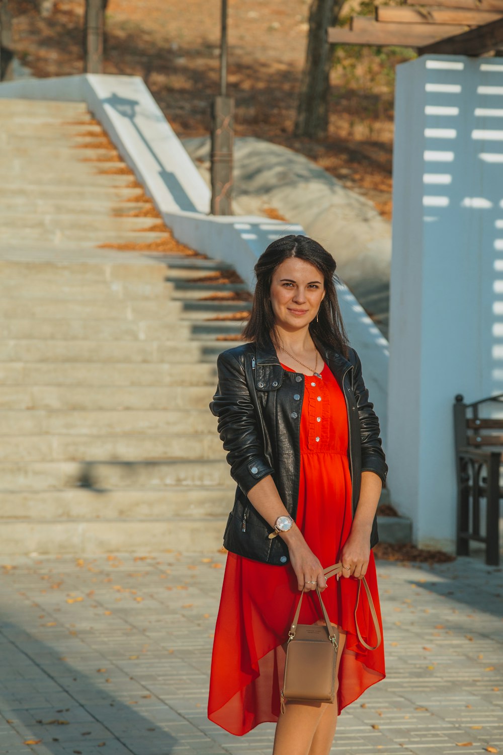 Foto mujer con chaqueta de cuero y vestido rojo parada la acera durante el día – Rusia gratis en Unsplash
