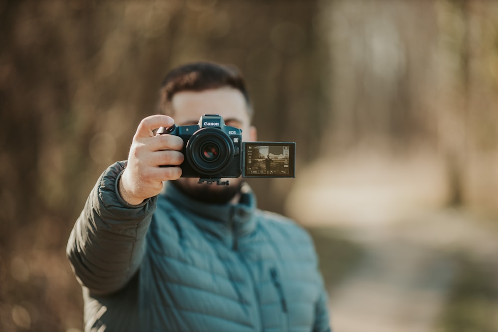 man in blue and white striped long sleeve shirt holding black camera