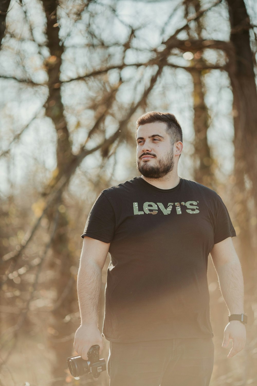 man in black crew neck t-shirt standing near trees during daytime