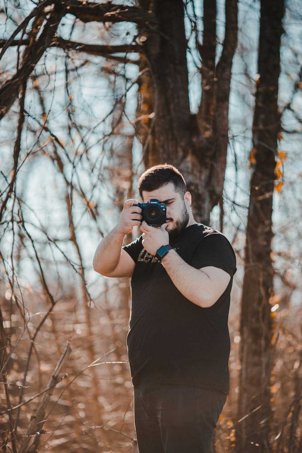 man in black t-shirt holding black dslr camera