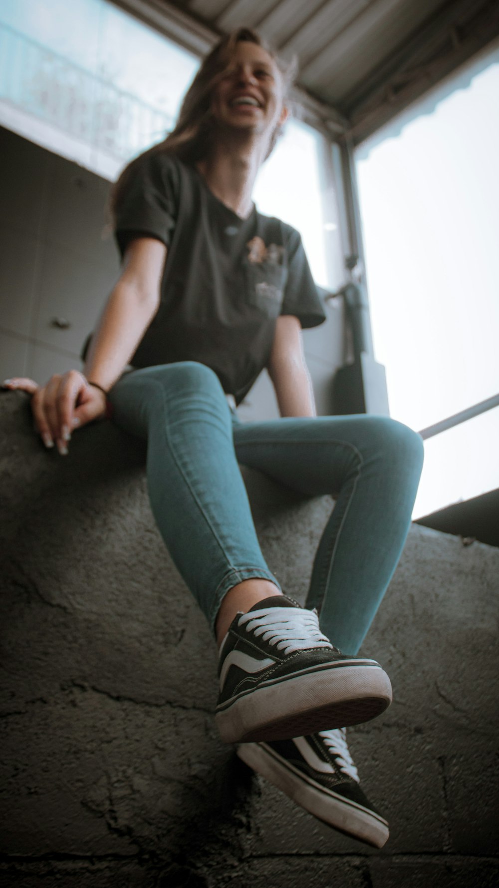 woman in black t-shirt and blue denim jeans sitting on gray carpet