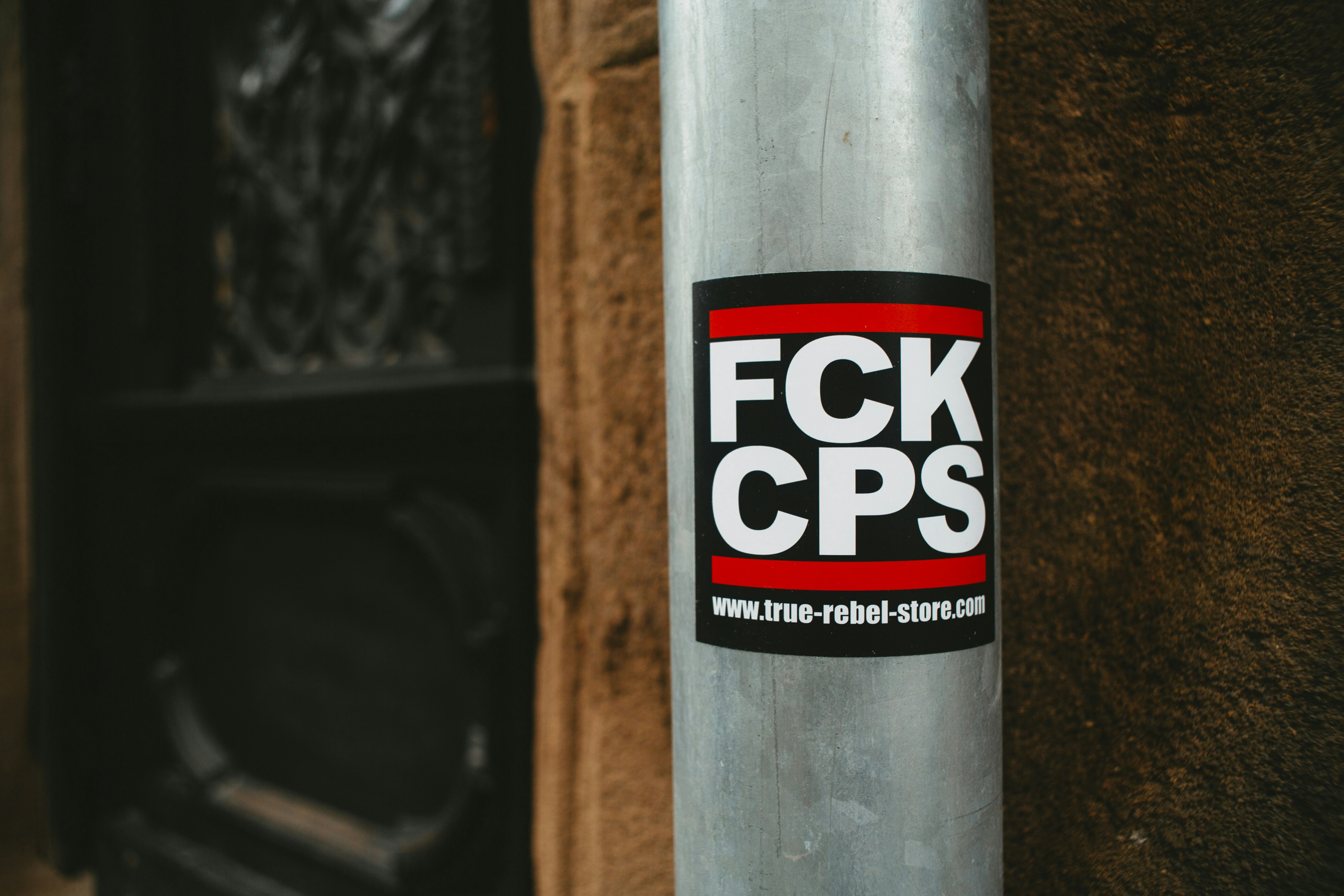 Urban stree art sticker: FCK CPS. Made with analog vintage lens, Leica Elmarit-R 2.8 28mm (Year: 1977)