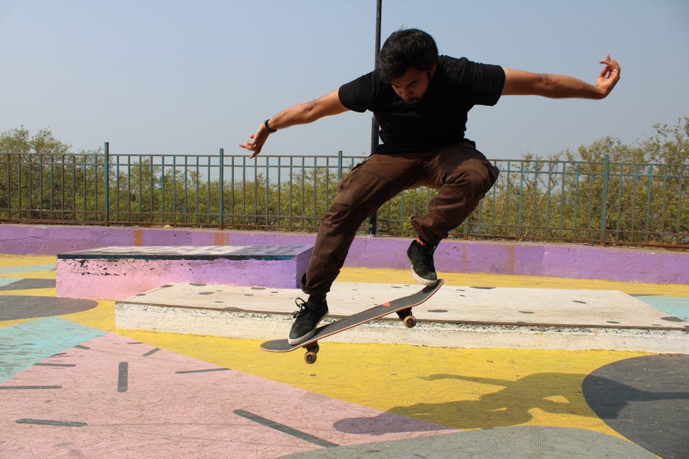 man in black t-shirt and black pants doing skateboard stunts