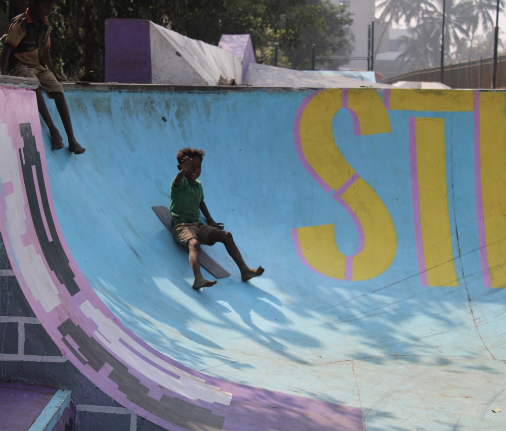 man in black t-shirt and black pants jumping on blue and green wall