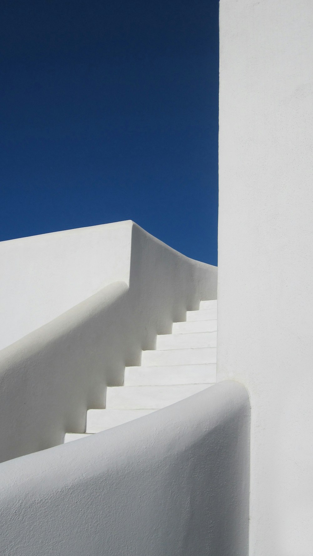 昼間の青空に浮かぶ白いコンクリートの階段