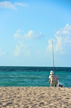 man in white t-shirt sitting on brown wooden bench on beach during daytime