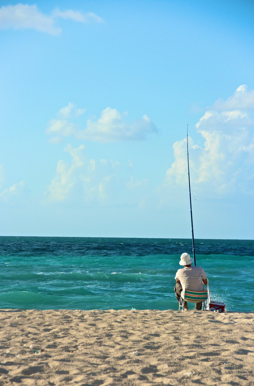 man in white t-shirt sitting on brown wooden bench on beach during daytime