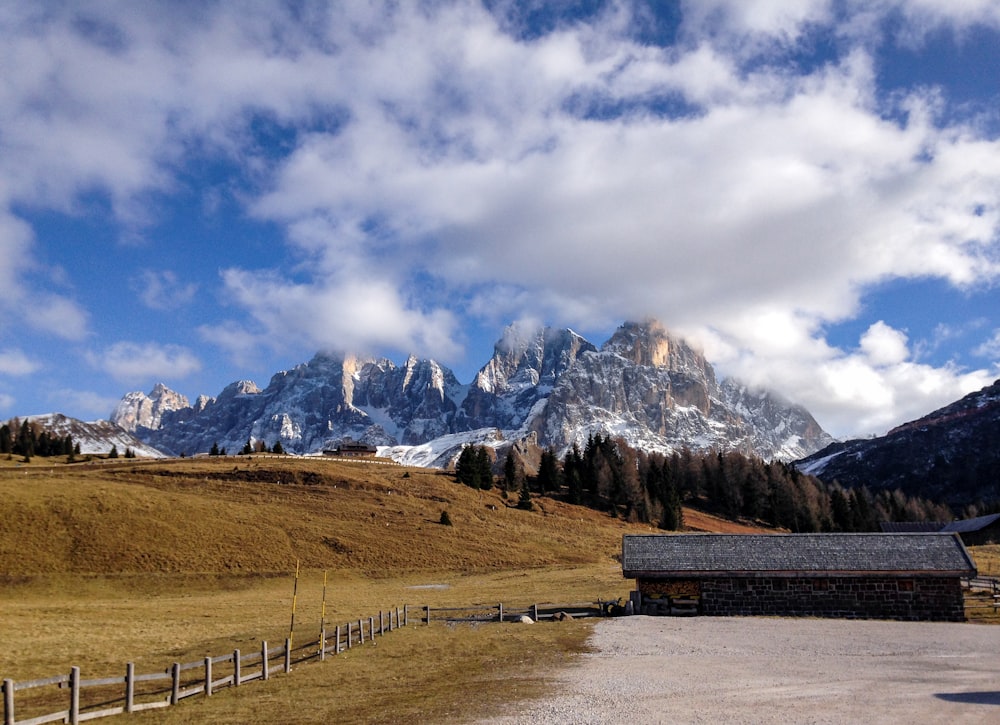 banco de madera marrón en campo marrón cerca de la montaña bajo nubes blancas y cielo azul durante el día