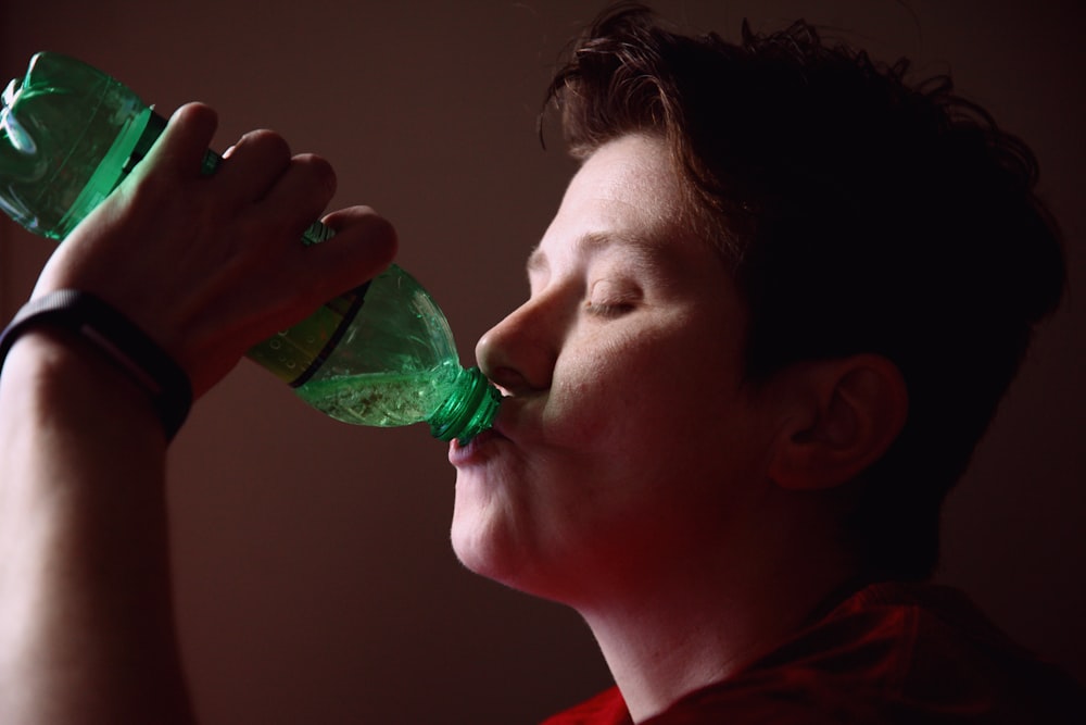 Mujer bebiendo de una botella de plástico verde