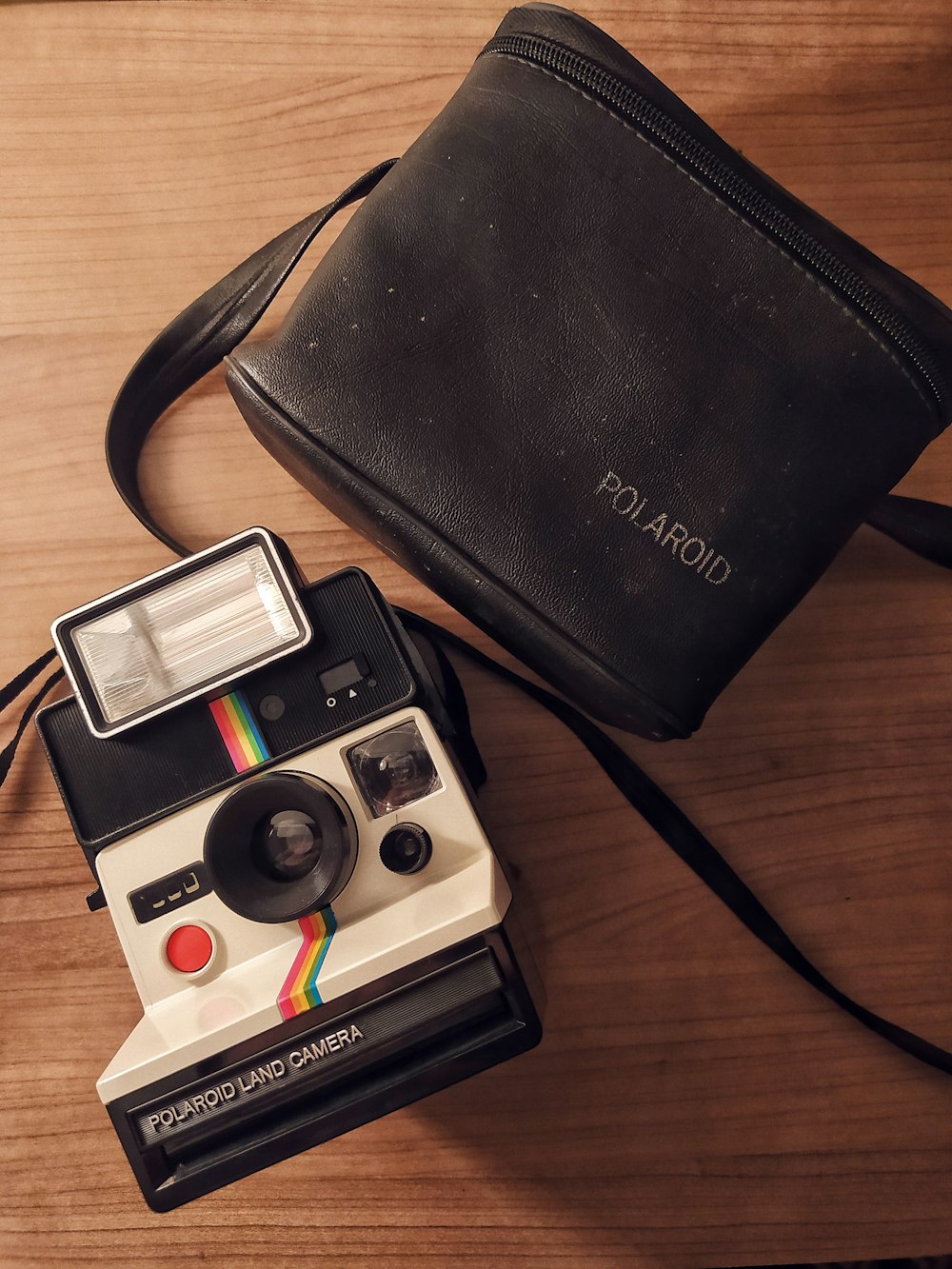 black and white polaroid camera beside black leather bifold wallet