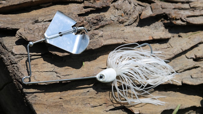 A close-up photo of a custom-painted fishing lure resting on a weathered wooden dock.