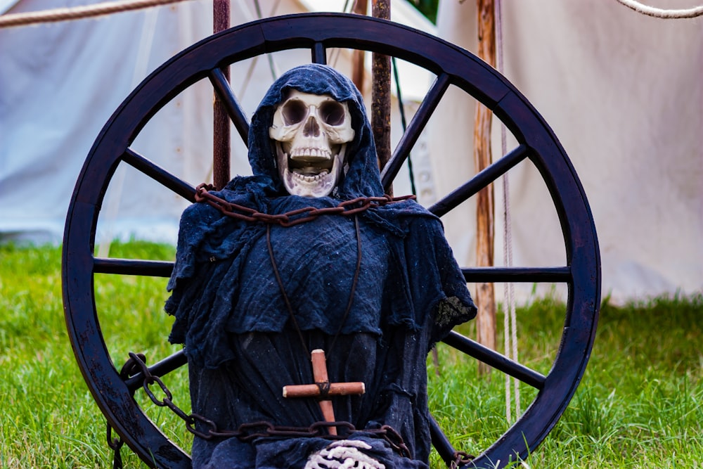 skeleton wearing blue and black coat and white mask sitting on black metal chair