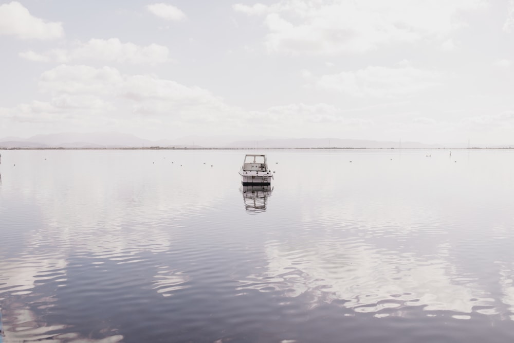 Bateau blanc sur l’eau calme sous les nuages blancs pendant la journée