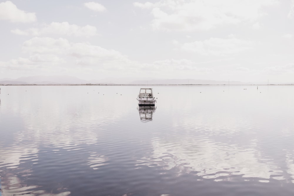 barco branco em águas calmas sob nuvens brancas durante o dia