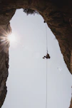 person in black jacket hanging on rope during daytime