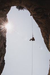 person in black jacket hanging on rope during daytime