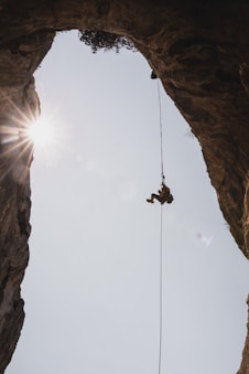 person in black jacket hanging on rope during daytime