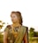 Happy Indian woman in traditional dress, standing outdoors with a serene background.