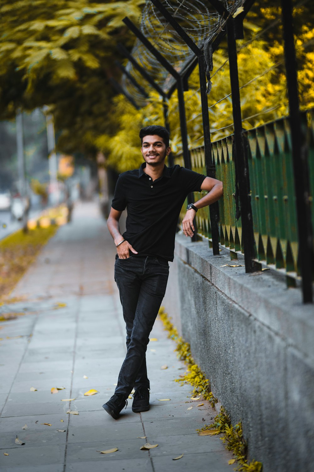 man in black crew neck t-shirt and blue denim jeans standing on gray concrete pathway