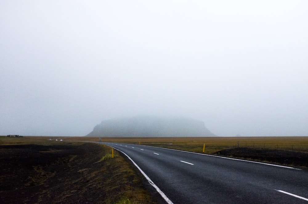 gray asphalt road between green grass field during daytime