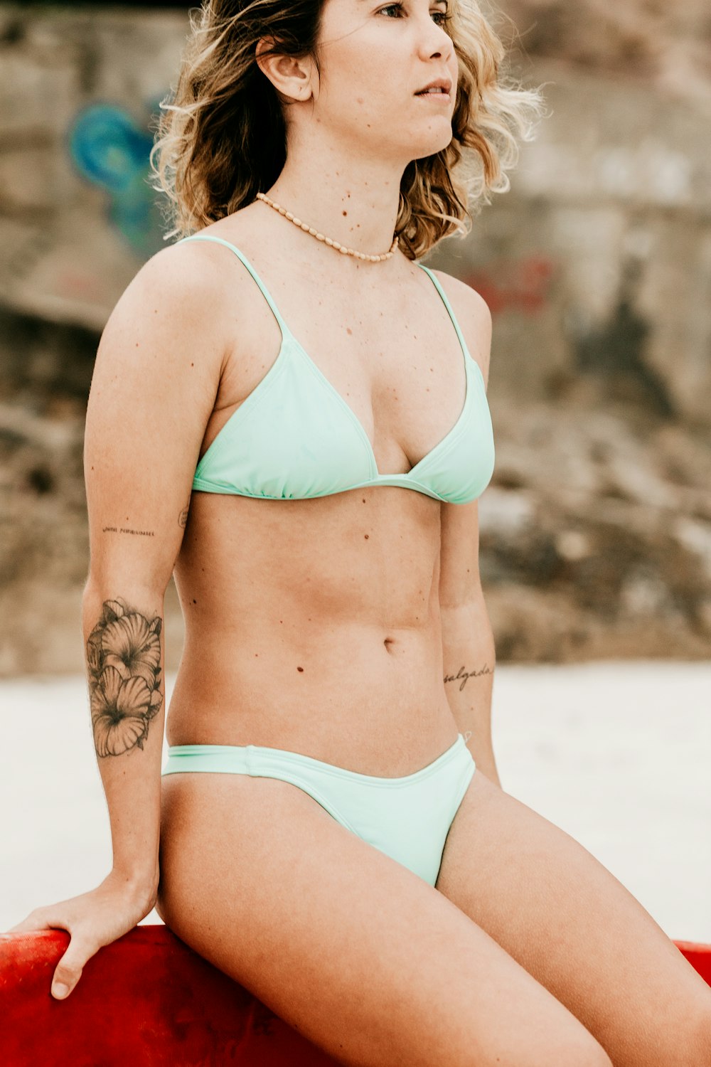 woman in teal bikini standing on sand during daytime