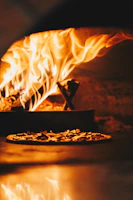 Close-up of the wood-fired oven glowing with flames inside the trattoria.