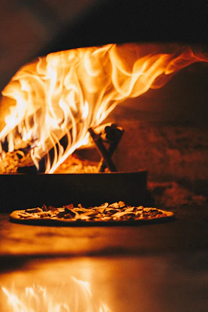Close-up of the wood-fired oven glowing with flames inside the trattoria.