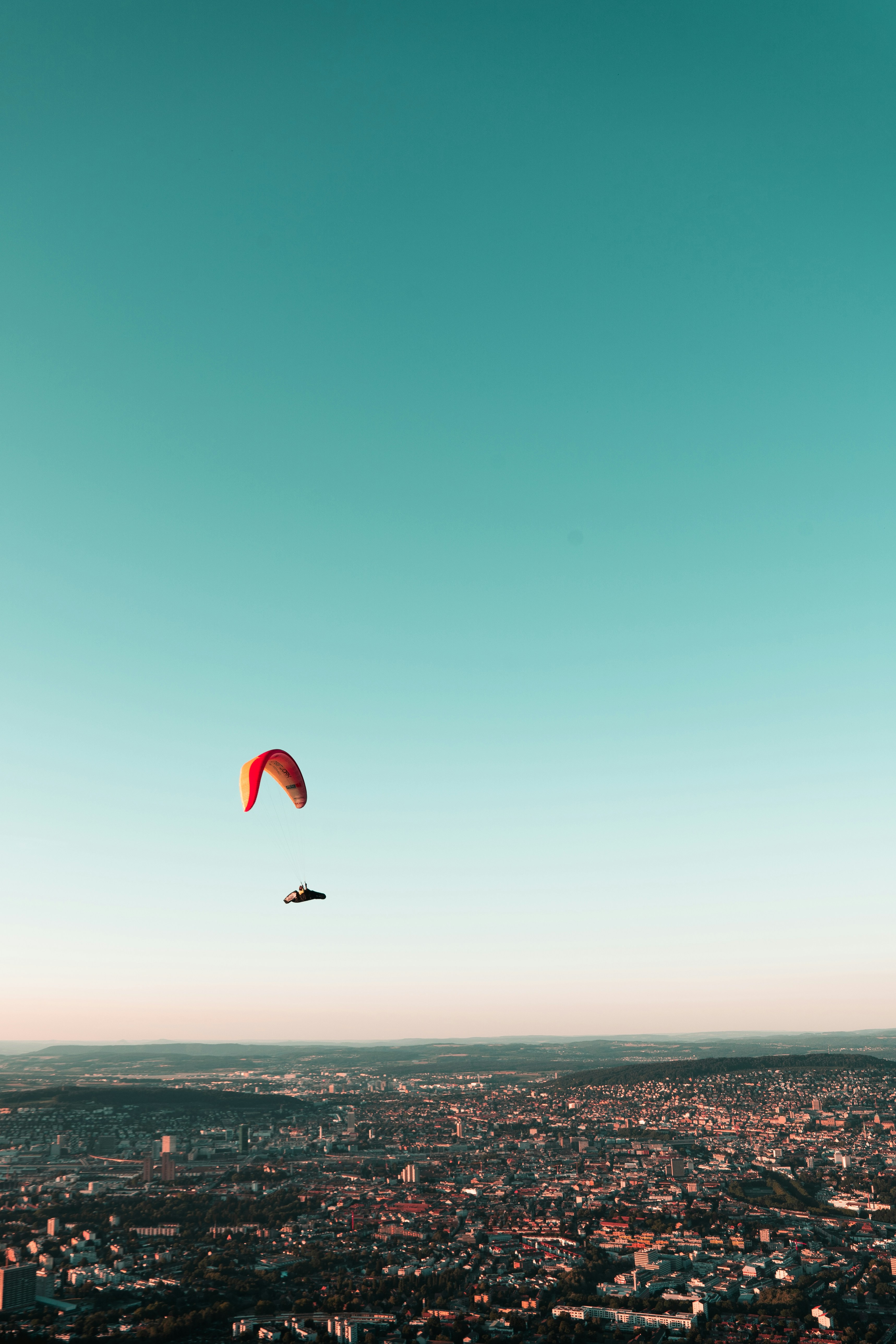 person in red parachute over sea during daytime
