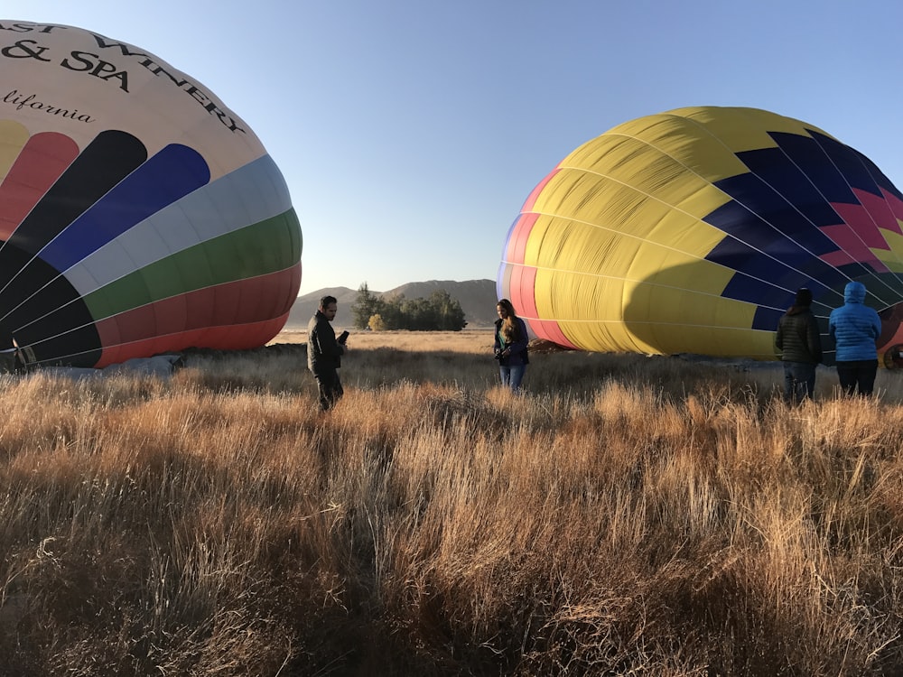 2 men standing beside hot air balloons during daytime