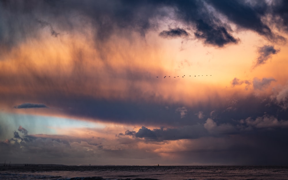 body of water under cloudy sky during sunset