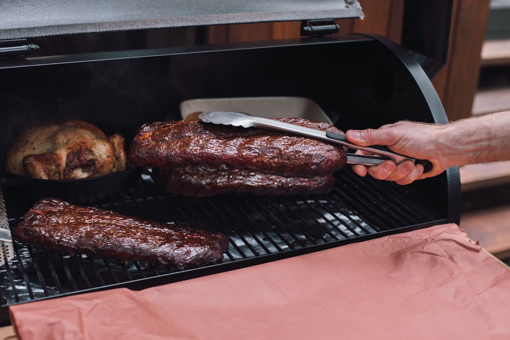 person holding fork and steak knife slicing meat